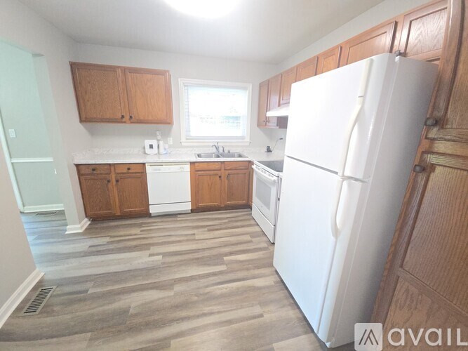 A kitchen with a white refrigerator and wooden cabinets.