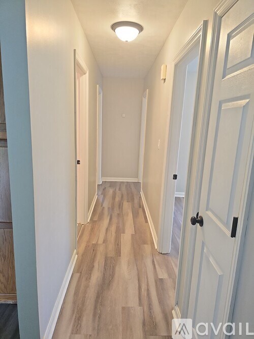 A long hallway with wood floors and white walls.