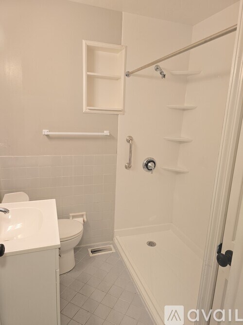 A white bathroom with a toilet, sink, and shower.