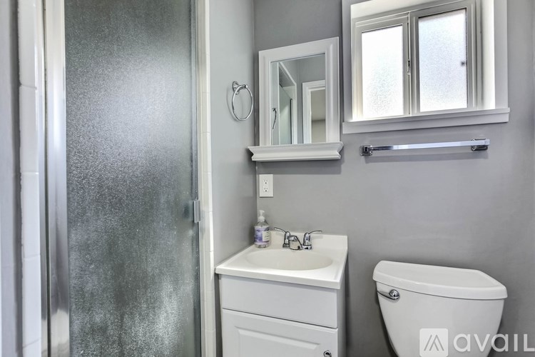 A bathroom with a toilet, sink, and mirror.