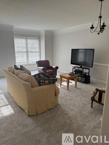 A living room with a couch, chair, and television.