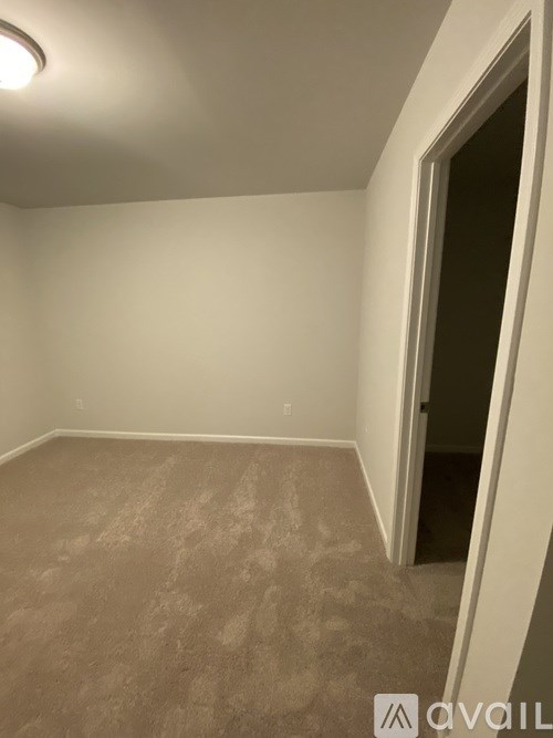 A room with carpeted floor and a door on the right side.