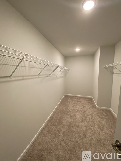 A hallway with a carpeted floor and white walls.