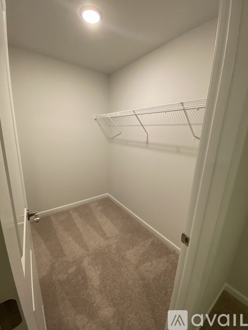 A small, empty room with a carpeted floor and a white door.