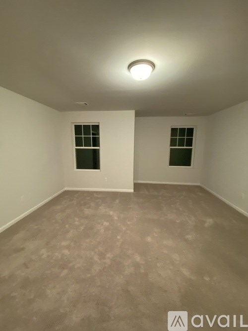 A room with a light on the ceiling and two windows.