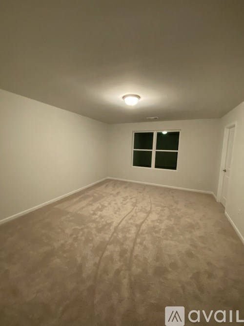 A room with a carpeted floor and a window with black blinds.