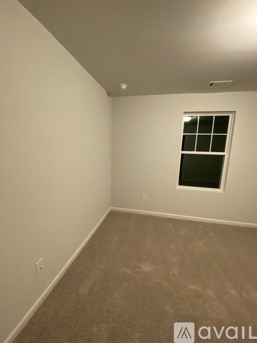 A room with a window and carpeted floor.