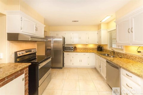 A kitchen with white cabinets and a granite countertop.