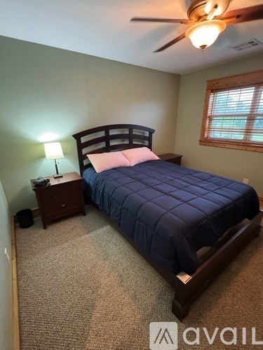 A bedroom with a bed, nightstand, and a ceiling fan.