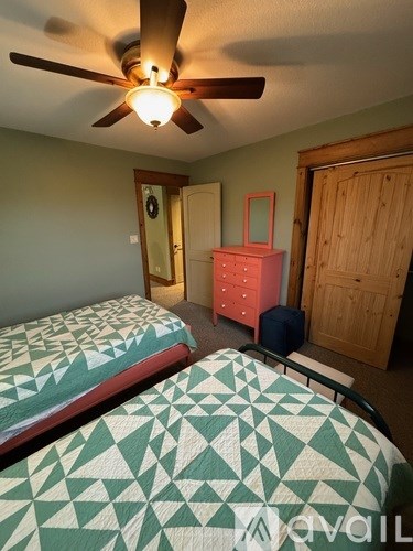 A bedroom with two beds and a ceiling fan.
