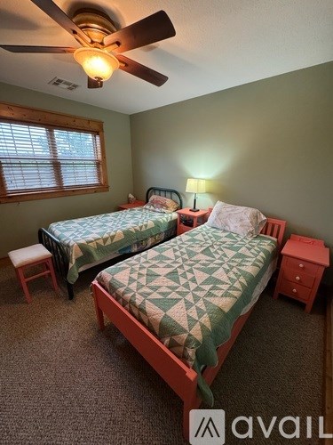 A bedroom with two beds and a ceiling fan.