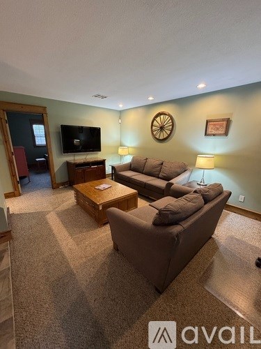 A living room with a couch, a coffee table, and a television.