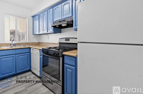 A kitchen with blue cabinets and a white refrigerator.