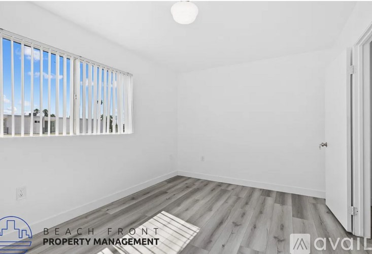 A room with wooden flooring and a window overlooking a beach.