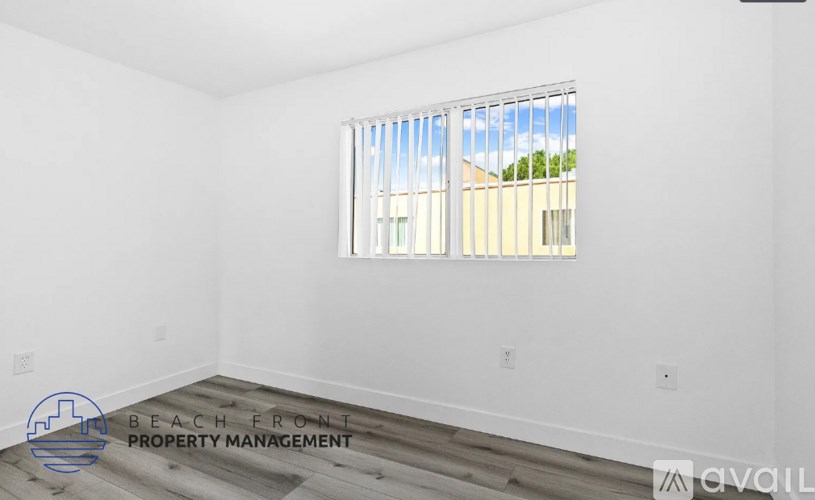 A room with a window showing a view of a building and trees outside.