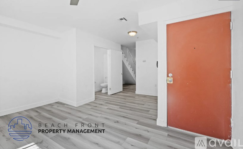 A room with a wooden floor and a white wall with a door on the right side.