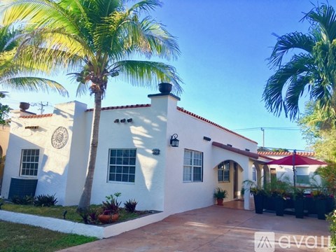 A white house with a palm tree in front.