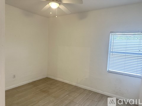 A room with a ceiling fan and a window with blinds.