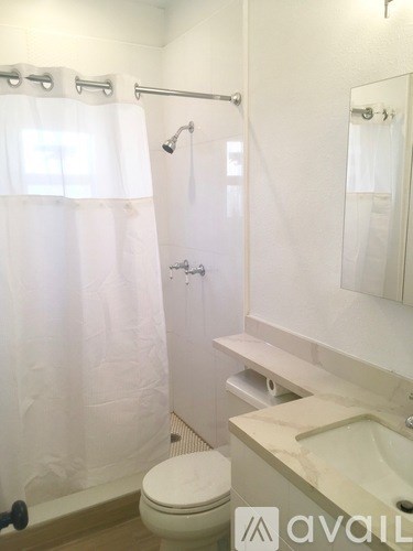 A white bathroom with a toilet, sink, and shower.