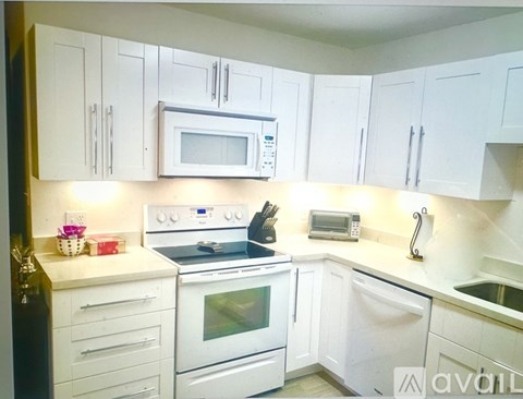 A kitchen with white cabinets and appliances.