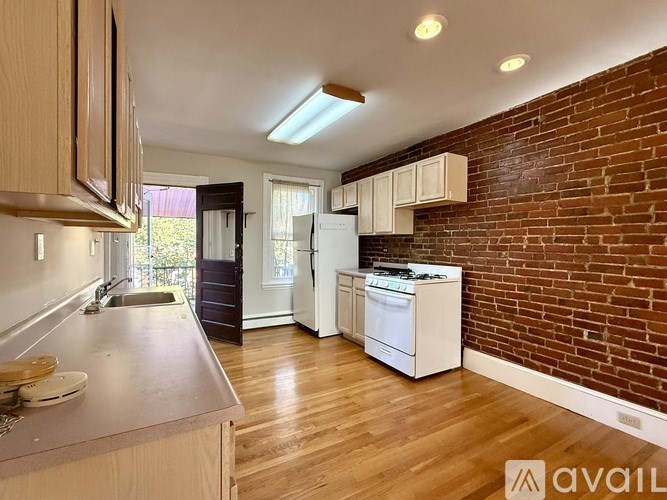 A room with wooden flooring and white walls, with a doorway leading to another room.