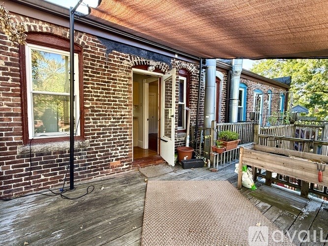 A wooden deck with a bench and a doorway leading to a porch.