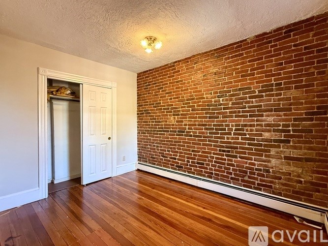 A room with a brick wall and wooden flooring.