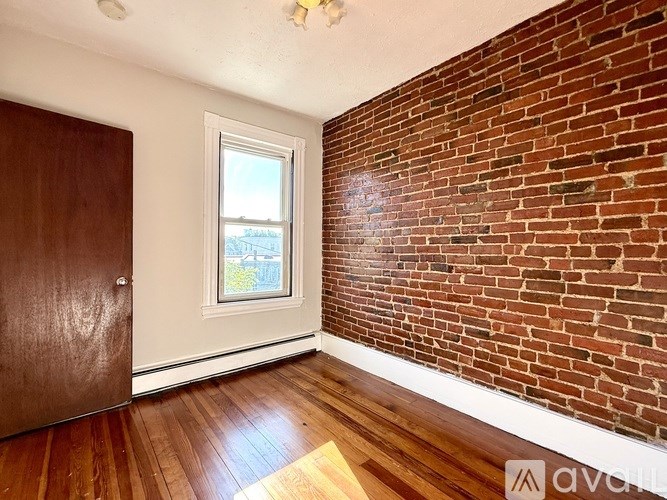 A room with a wooden floor and a brick wall.
