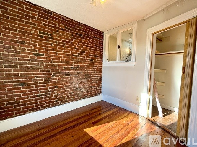 A room with a brick wall and wooden flooring.