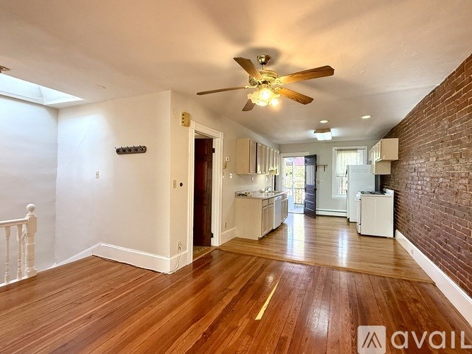 A long hallway with wood floors and a ceiling fan.