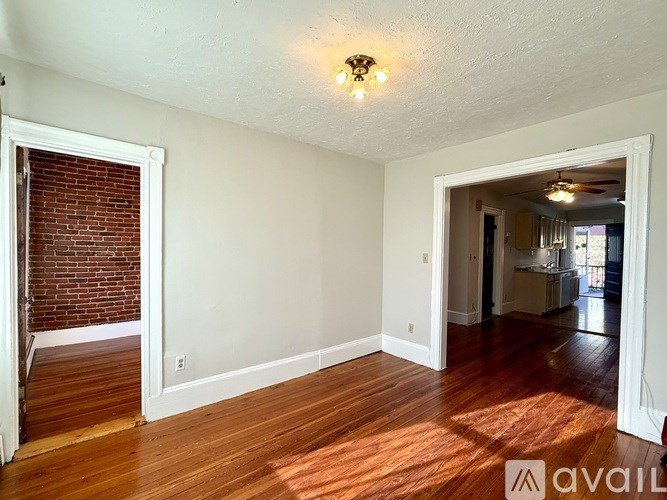 A room with wooden flooring and a view into another room.