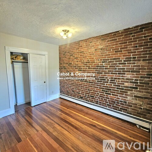 A room with wooden floors and a brick wall.
