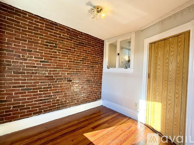 A room with wooden floors and a brick wall on one side.