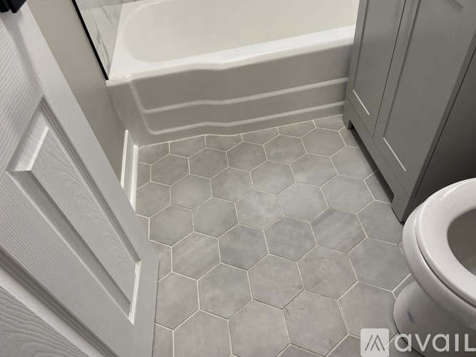 A bathroom with a hexagonal tile floor and a toilet.