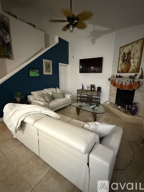 A living room with a white couch and a fan.