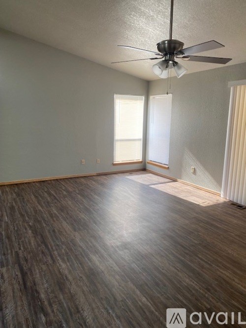 A room with a ceiling fan and wooden flooring.