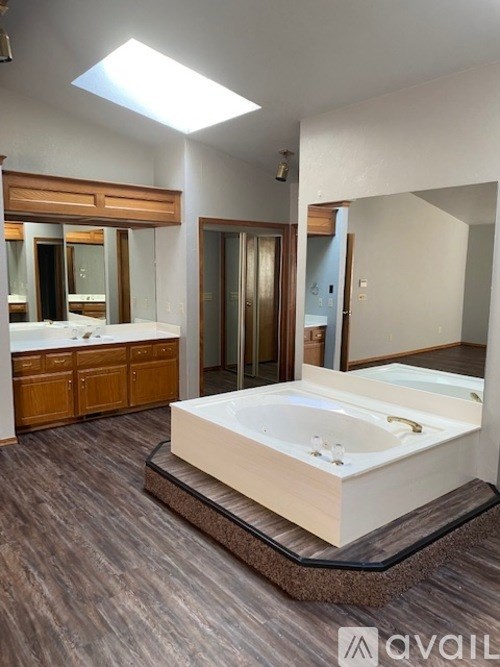A modern bathroom with a skylight and a large bathtub.