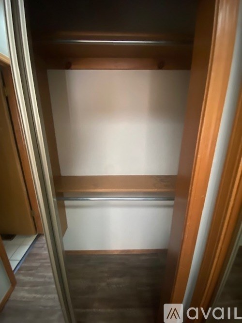 A wooden closet with a mirror on the door.
