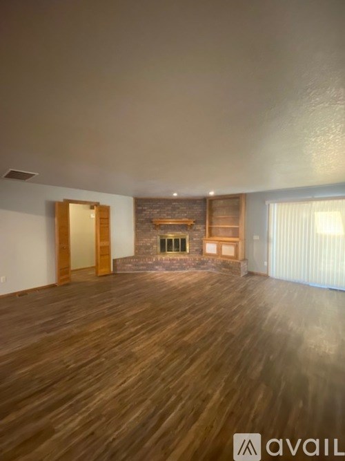A room with wooden floors and a stone fireplace.