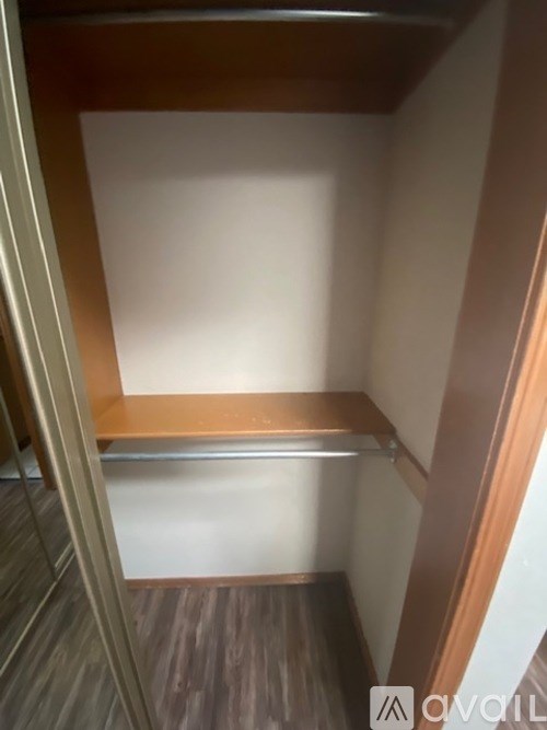 A small, empty room with a wooden floor and a shelf.