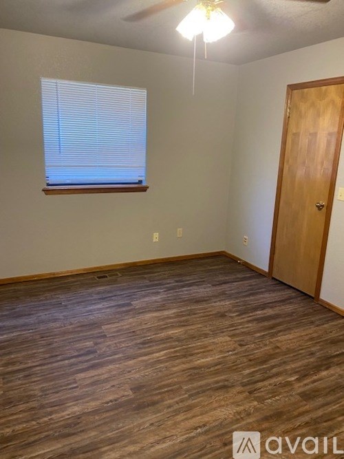 A room with wooden flooring and a window with blinds.