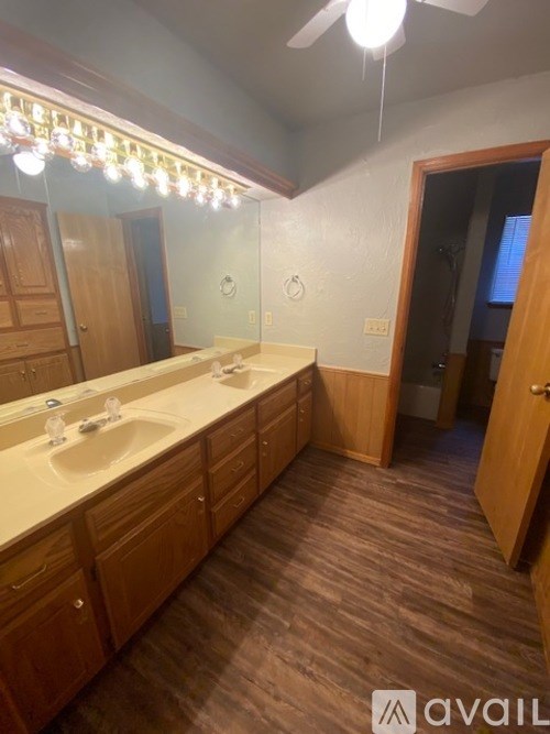 A bathroom with wooden cabinets and a vanity with two sinks.