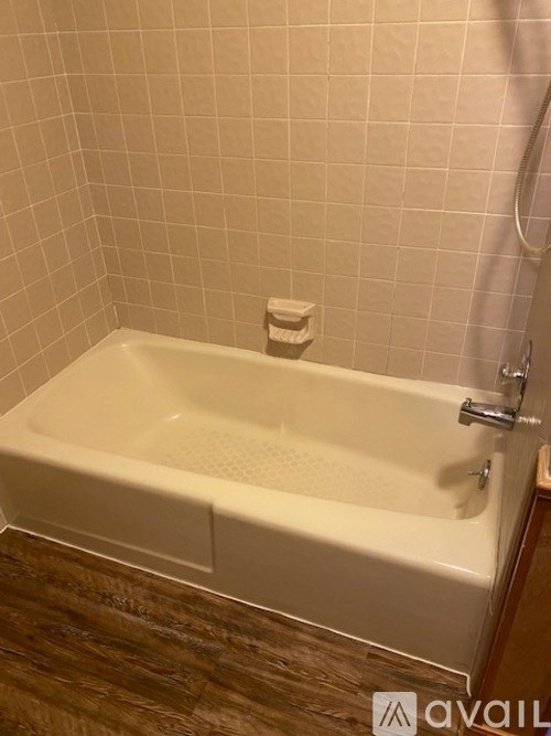 A white bathtub with a shower head and a faucet.