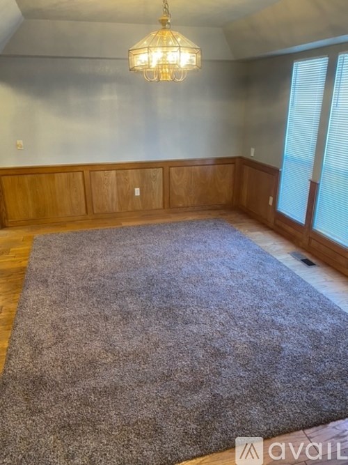 A room with a grey rug and wooden panels on the wall.
