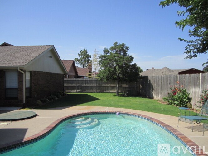 A small residential pool with a patio and a house in the background.