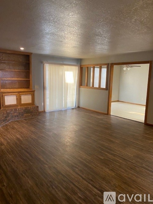 A room with wooden floors and a large window with blinds.
