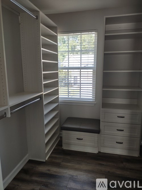 A room with a bench and drawers under a window.