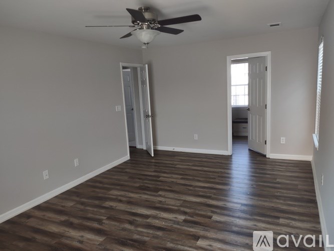 A room with a ceiling fan and wooden flooring.