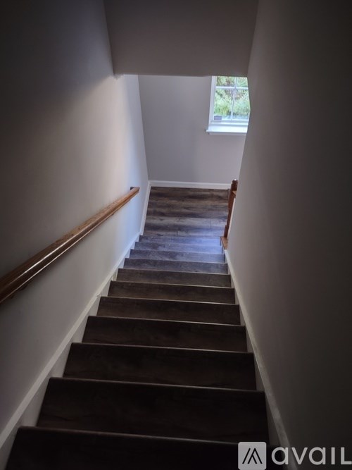 A staircase with a wooden handrail and a window in the background.