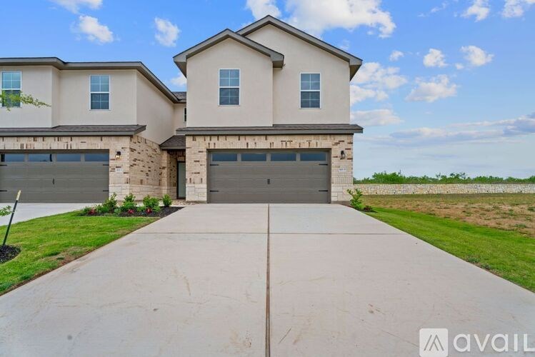 A modern house with a large driveway in front.